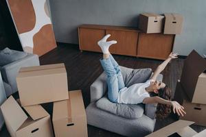 Excited woman celebrates relocation to new home, rejoicing surrounded by carton boxes on moving day photo