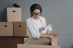 Hispanic female packing items in carton box on relocation day. Moving, renovation, mortgage concept photo