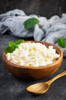 Bowl of cottage cheese on dark background. Fresh homemade cottage cheese photo