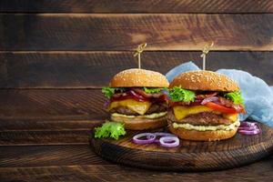 Delicious beef hamburger with bacon slice, cheese, lettuce and tomato. Tasty fastfood burger photo