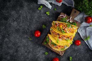 tacos mexicanos con tortilla de maíz. tortilla con carne de pollo, choclo, lechuga y cebolla. vista superior foto