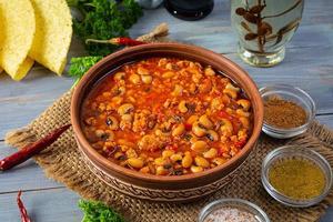 Chili con carne in a bowl on wooden background. Mexican cuisine photo