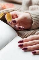 Hands of a young woman with dark red manicure on nails photo