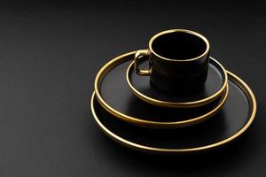 A set of black and golden ceramic plates and cup on a black background photo