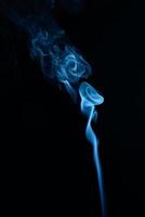 A vertical shot of blue tobacco smoke on a black background photo