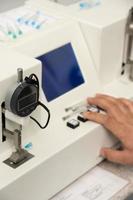 A vertical shot of a hand using a medical machine to test and manufacture pharmaceutical syringes photo