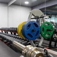 A vertical closeup of weight plates and dumbbells in the sports complex photo