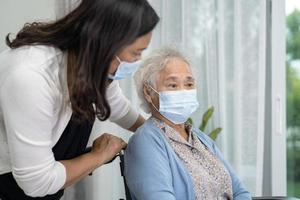 Help Asian senior or elderly old lady woman sitting on wheelchair and wearing a face mask for protect safety infection Covid19 Coronavirus. photo