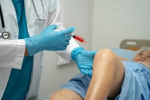 Asian doctor inject Hyaluronic acid platelet rich plasma into the knee of senior woman to walk without pain. photo