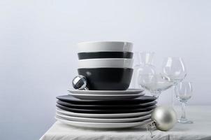 juego de vajilla en blanco y negro con platos, cubiertos y vasos con decoraciones navideñas en la mesa de comedor, espacio para copiar foto