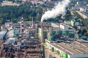 aerial panoramic view on smoke pipes of a woodworking factory on the bank of a wide river photo