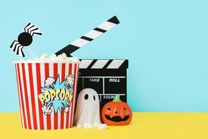 Halloween concept background. Movie clapperboard with popcorn, funny halloween pumpkin and halloween ghost. Halloween movies concept photo