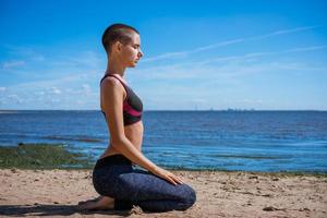 Young slim woman doing yoga outdoors on sandy shore bay on sunny day. Unity photo