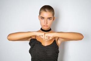 Portrait of a young woman with a short haircut with clenched fists on a light background photo