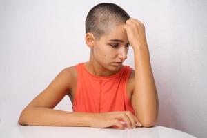 Caucasian girl with short hair, almost bald, holds her hands behind her head photo