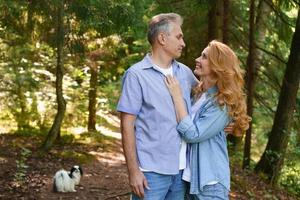 Happy old elderly caucasian couple smiling in park on sunny day cuddling photo