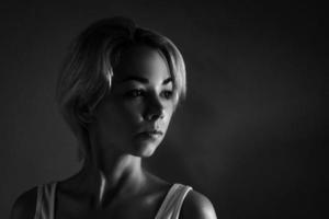 Female portrait close-up looks away, black and white photo dark