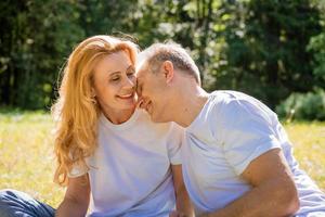 sonriente feliz pareja madura disfrutando de un picnic. medio sentado en una manta de picnic foto