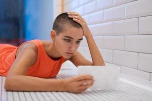 Young woman lies on tile and reads letter with anxiety, received bad news. Girl photo