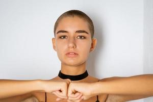 Portrait of a young woman with a short haircut with clenched fists on a light background photo