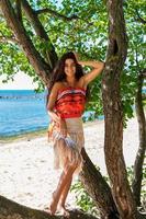 happy tanned girl stands by a tree on the beach photo