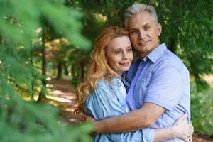 feliz pareja de ancianos caucásicos sonriendo en el parque en un día soleado caricias foto