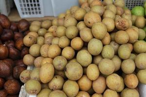 Fruto de sapodilla saludable y fresco perfectamente arreglado para la venta en el mercado. fondo de fruta sana y fresca foto