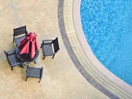 vista de ángulo alto de sillas con sombrilla en la terraza de la piscina foto