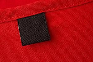 Blank black laundry care clothes label on red fabric texture background photo