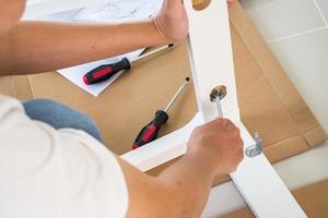 hombre montando muebles de silla blanca en casa foto