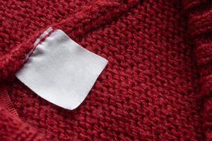 Blank laundry care clothes label on red knitted fabric texture background photo