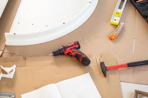 Cordless screwdriver and tool on cardboard paper assembly furniture concept photo