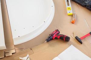 Cordless screwdriver and tool on cardboard paper assembly furniture concept photo