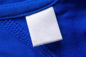 etiqueta de ropa blanca en blanco para el cuidado de la ropa sobre fondo de textura de tela azul foto