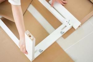 Man assembling white chair furniture at home photo