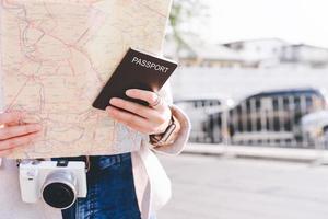 Young adult asian woman hand holding passport and map for travel in city. photo