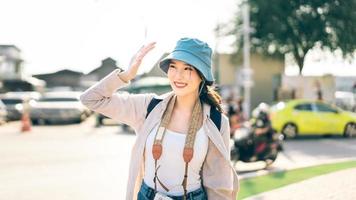 Walking young adult southeast asian woman traveller wear blue hat and backpack under sunlight photo
