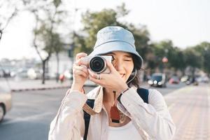 Attractive young adult asian woman traveller using camera for photo journey.