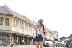 Walking young adult southeast asian woman traveller wear blue hat and backpack under sunlight photo