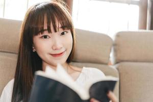 mujer adolescente asiática leyendo un libro para aprender y estudiar en casa. foto