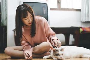 Young adult asian woman playing with lovely cat at home. photo