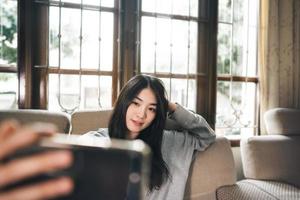 foto selfie de mujer asiática adulta joven por teléfono móvil en casa