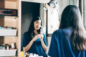 retrato de solo alambiques bienestar mujer adulta joven asiática maquillaje antes del espejo en casa