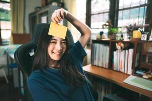 Young adult freelancer woman hold a paper note on face in office at home. photo