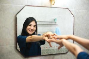 Young adult smile asian woman practice self talk conversation in the morning in bathroom at home. photo