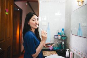 Young adult asian woman brushing teeth in bathroom photo