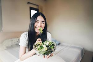 Young adult asian woman eat vegetable salad breakfast for diet photo