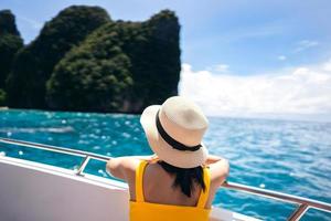 Rear view of adult traveling woman relax on the sailing boat with summer island and sea photo