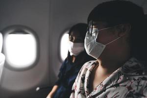 Traveller adult asian couple man and woman wear mask on airplane near window photo