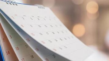 Close up white paper desk calendar with blurred bokeh background appointment and business meeting concept photo